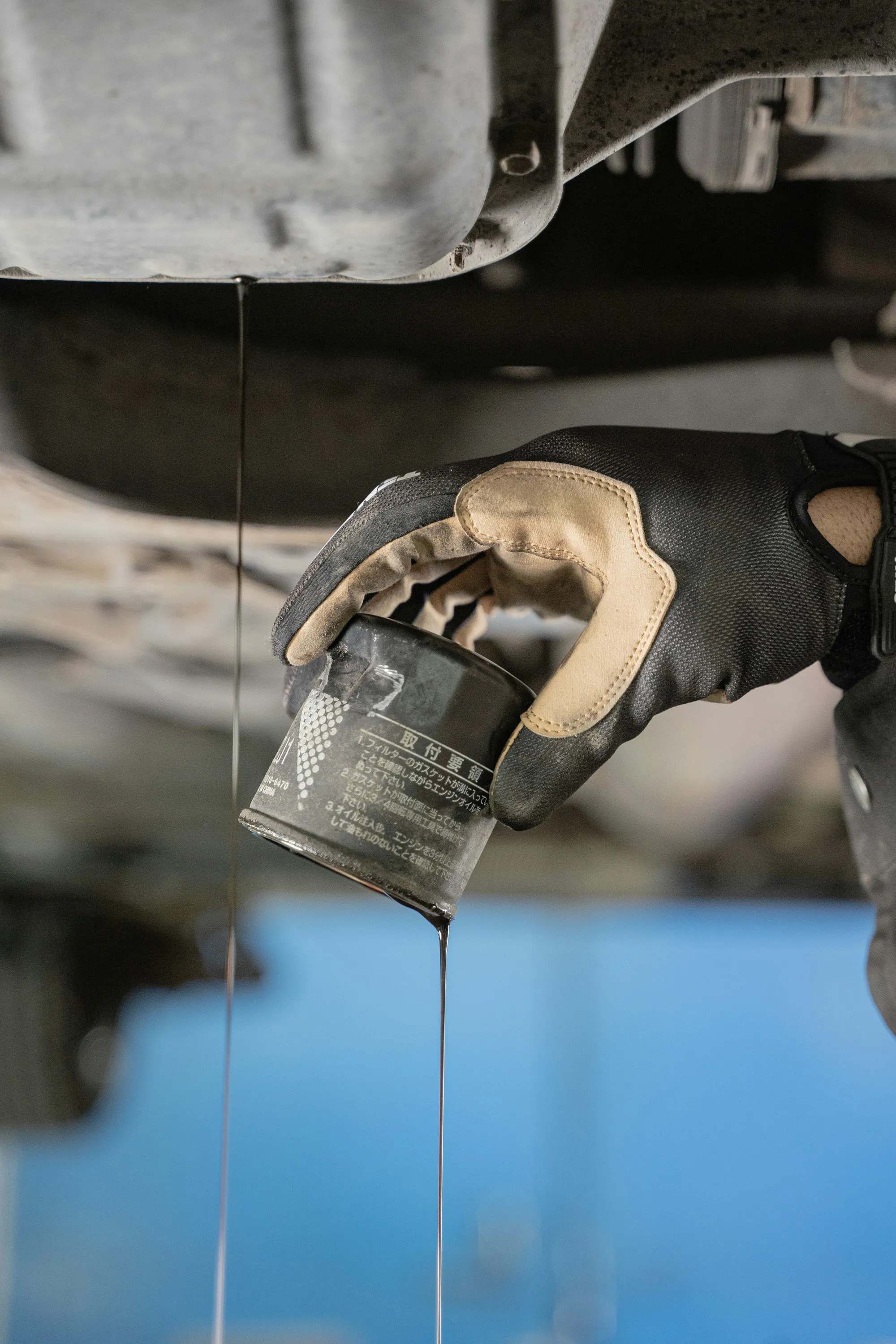 Mechanic's gloved hand removing an oil filter